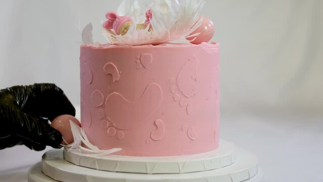 decoration of a cake for a family christening pink cake with footprints of small child on top of angel wings and baby in pink diaper a girl how to find out gender of child with help of a cake