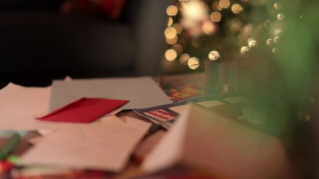 Envelope and letter to Santa Claus next to Christmas tree. Panning shot 