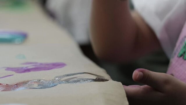 Slow motion shot of a young girl painting a figure with paint on a piece of paper