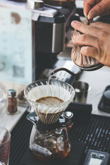 Drip filter coffee brewing. hand of barista pouring hot water over filter with ground coffee. pouring hot water over ground coffee beans contained in filter. Close up view