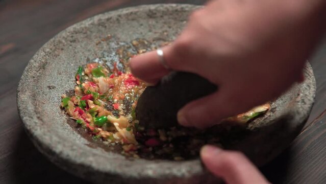 Close up the chef is pounding chili sauce. Sambal is a famous food from Indonesia
