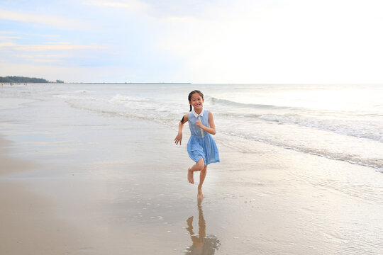 Asian young girl kid having fun running on tropical sand beach