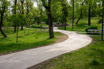 Winding walking concrete path in a summer park.