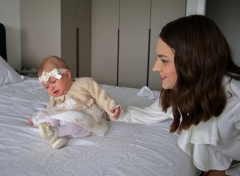 Mother playing with her baby girl ready for christening