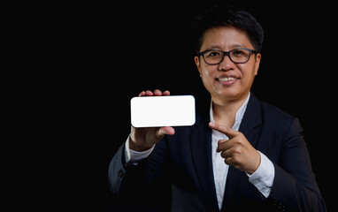 Businesswoman with short black hair shows a smartphone with a smile while standing on a black...