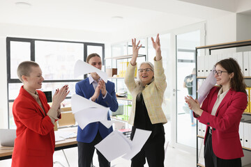 Mature manager throws up papers while colleagues applaud