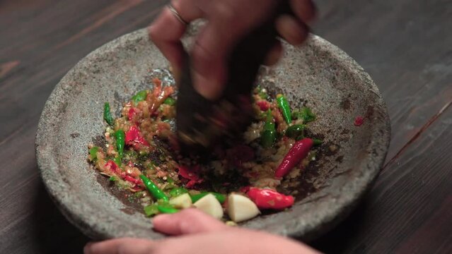 Close up the chef is pounding chili sauce. Sambal is a famous food from Indonesia