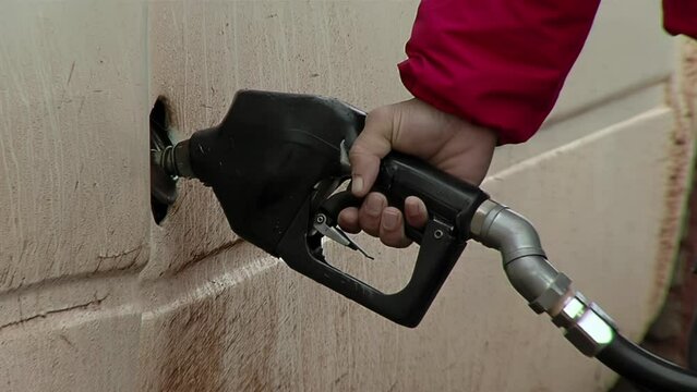 Man Hand Holding Gas Pump Handle and Filling the Fuel Tank on Vehicle. Close Up.