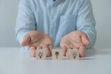 Idea concept with vision, innovation and inspiration. Businessman showing or sharing ideas with light bulb on wooden cube blocks. innovative technology in science and communication concept.