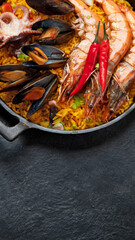 Traditional spanish seafood paella in the fry pan on a black background.