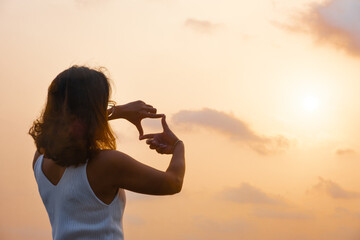 Woman covering her hands, posing, framing frame, with sunset Planning and foreseeing the future
