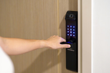 Hand using smart digital door lock while open or close the door at home or apartment. NFC...