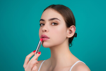 Obraz premium Lipstick, beauty and cosmetics. Beautiful woman applying lipstick on lips. Mockup for cosmetics, makeup. Lips color product, balm cosmetic on studio background.