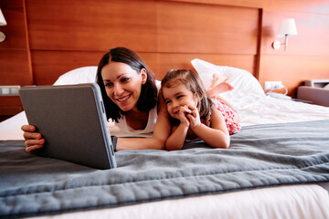 Little girl and her mother using an iPad in a hotel room