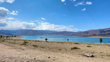 View of a beautiful blue lake in the mountains. Amazing summer landscape. Blue sky and white clouds.