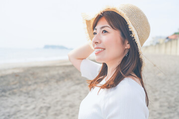 Fototapeta na wymiar 海辺で過ごす麦わら帽子を被った女性の横顔