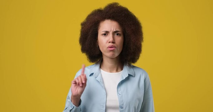 Young african american woman saying no with in dex finger gesture standing over orange studio background