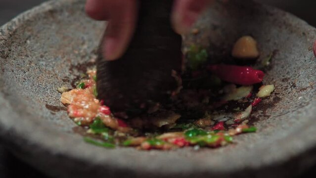 Close up the chef is pounding chili sauce. Sambal is a famous food from Indonesia
