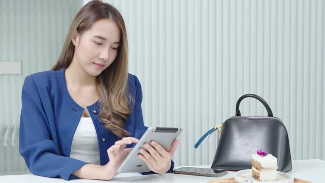 Beautiful young lady working on tablet at cafes.