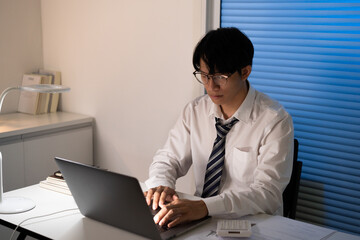 Asian businessman working on laptop in night office. dark late night at home office online meeting work hard concept.