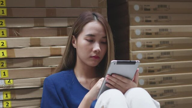 Asian woman using tablet looking up stock taking inventory in warehouse shopping. logistic industry and business import export.