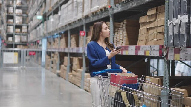 Asian woman using telephone looking up stock taking inventory in warehouse shopping. logistic industry and business import export.