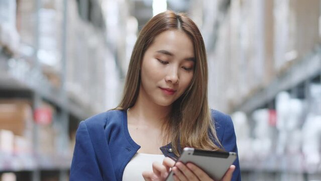 Asian woman using tablet looking up stock taking inventory in factory. logistic business shipping and delivery logistic service.