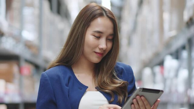 Asian woman using tablet looking up stock taking inventory in factory. logistic business shipping and delivery logistic service.