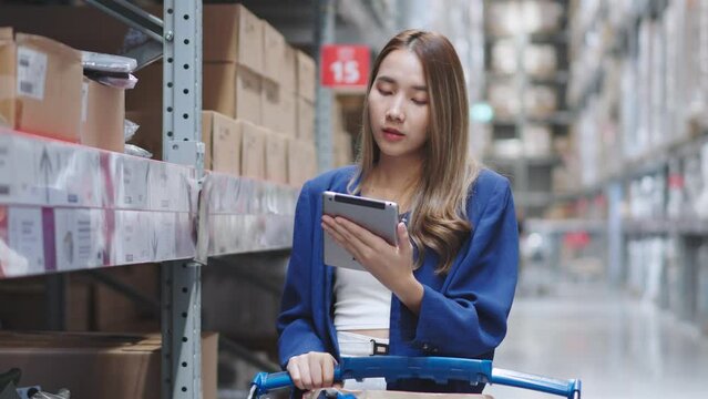 Asian woman using tablet looking up stock taking inventory in factory. logistic business shipping and delivery logistic service.