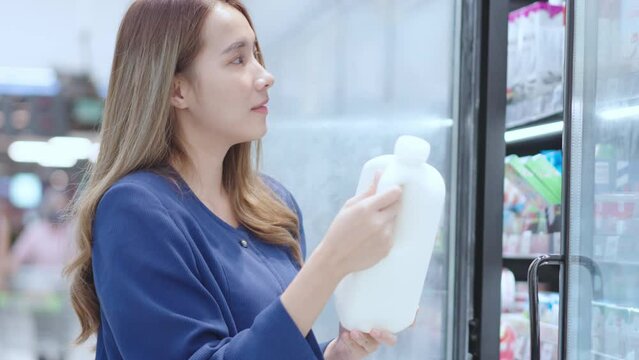 Asian woman shopping at Supermaket store buy choose dairy products.