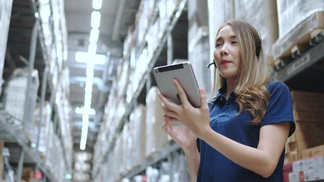 Asian female using tablet checking amount of stock product inventory on shelf at distribution warehouse factory. logistic business shipping and delivery logistic service.