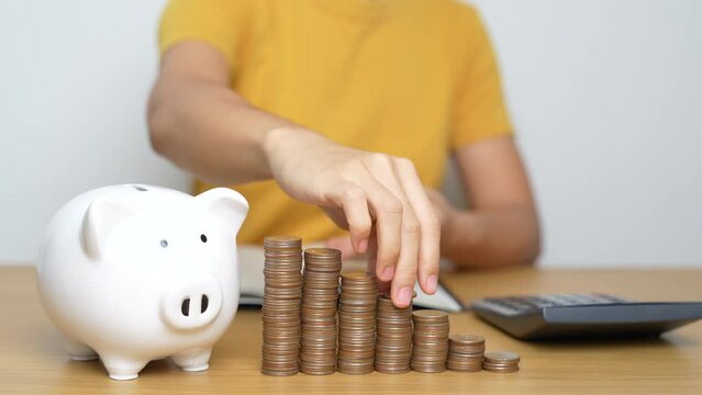 Money Saving for Future Plan, Retirement fund, Pension, Investment, Wealth Business and Financial concepts. Woman Counting and calculate money with coins stack with piggy bank for deposit