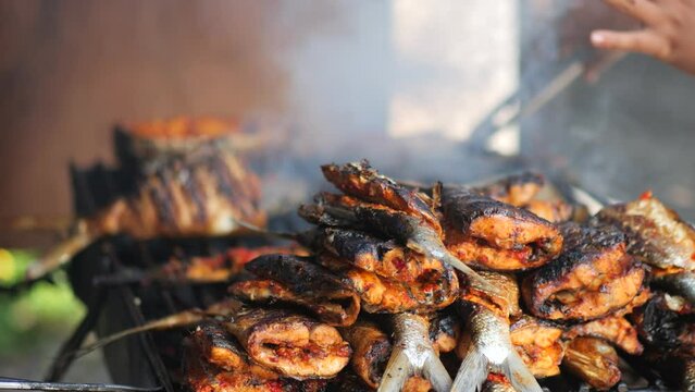 Close-up shot of cooking fish. Baking and roasting marinated fish on barbecue grill. Sea bass or grouper grilled over charcoal. 4K