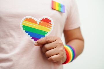 Asian woman holding red heart with rainbow flag, LGBT symbol rights and gender equality, LGBT Pride Month in June.