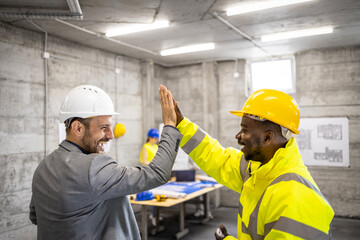 Construction worker and structural engineer giving a high five after successfully completing building project. - obrazy, fototapety, plakaty