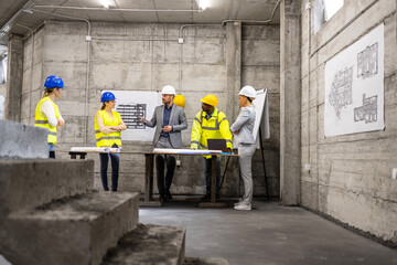 Construction site meeting. Team of experienced architects, engineers and workers brainstorming and sharing new ideas.