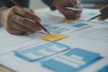 Close up ux developer and ui designer brainstorming about mobile app interface wireframe design on...