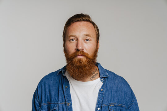 Mid bearded man in denim shirt looking at camera standing isolated
