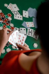 young girl in a new dress and hat deals cards at a poker game at a green table. poker game concept