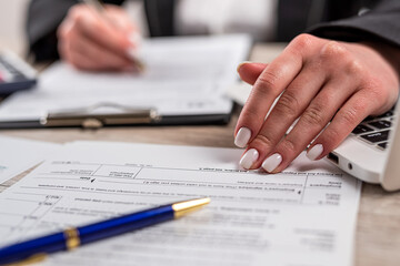 closeup woman filling 1040 tax form at office