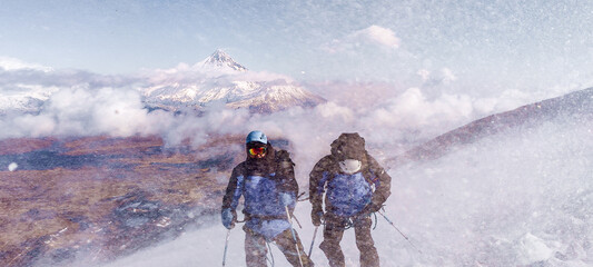 Climber fights with bad weather in the winter mountains