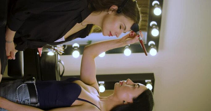 Vertical footage of a make up artist work in her beauty studio with client.