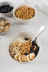 Homemade granola with Greek yogurt, almonds, blueberries and banana in a bowl. 