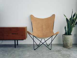 Stylish leather chair chair in a modern interior with white walls and concrete floor, wooden...