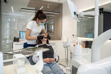 female dentist examines the teeth of a girl patient with tools in dentistry.