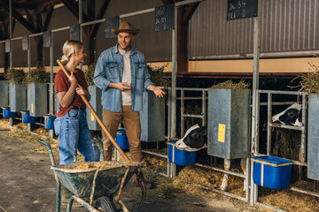 A woman cleans a cow nursery and a farmer talks to her about calves.