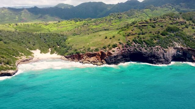 Aerial of Mahaulepu Beach secluded beach Koloa Kauai Hawaii USA. Aerial landscape of an island with mountains, cliffs, white sandy beach, tropical forest, ocean and clouds