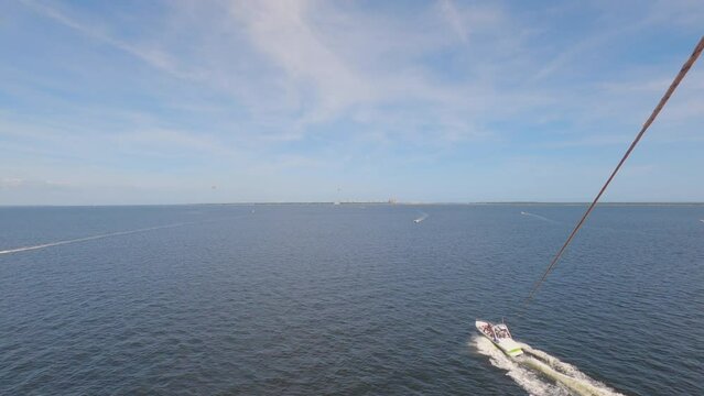 POV of person flying in air pulled from boat parasailing in Florida, sunny day