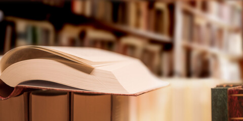 An open book on the bookshelf background in interior, close-up. © Baurzhan I