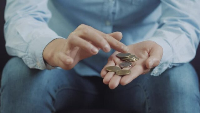female person counts small coins lying on palmsitting on the sofa